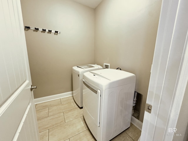 clothes washing area featuring light tile patterned flooring, laundry area, independent washer and dryer, and baseboards