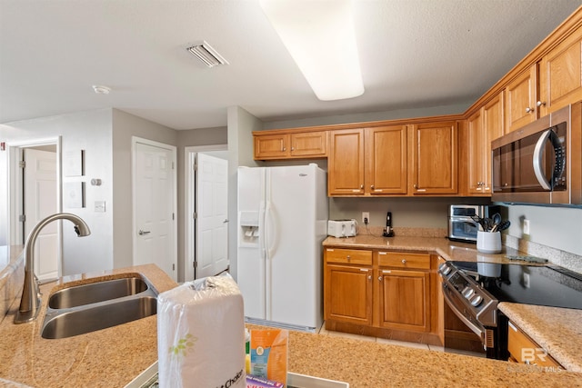 kitchen featuring white refrigerator with ice dispenser, a textured ceiling, black electric range oven, and sink