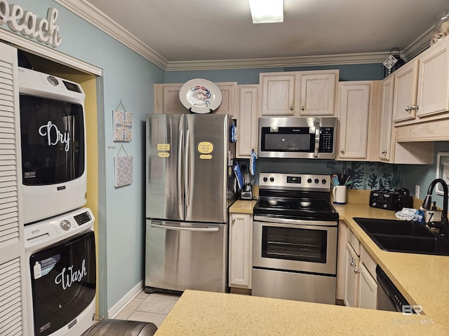 kitchen featuring appliances with stainless steel finishes, light tile patterned floors, stacked washer and clothes dryer, ornamental molding, and sink