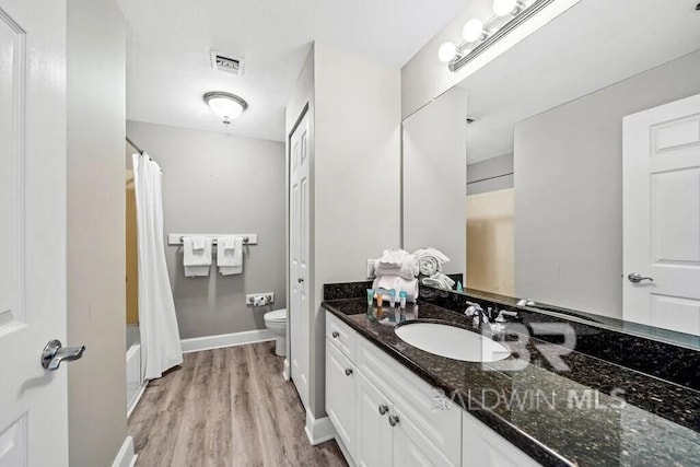 full bathroom with toilet, wood finished floors, visible vents, vanity, and baseboards