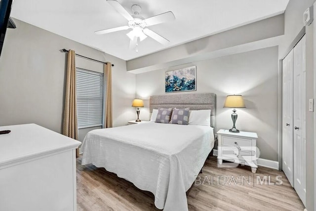 bedroom featuring a ceiling fan, a closet, baseboards, and wood finished floors