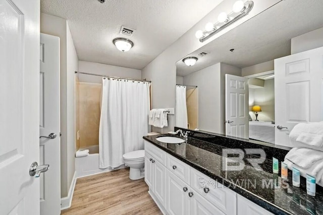 bathroom featuring toilet, shower / tub combo with curtain, wood finished floors, a textured ceiling, and vanity