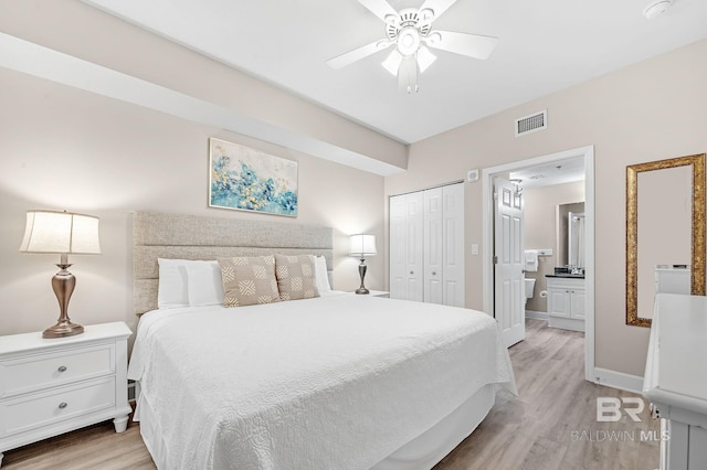 bedroom with light wood-type flooring, connected bathroom, visible vents, and a closet