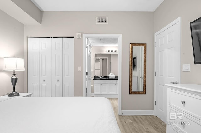 bedroom featuring a closet, visible vents, light wood-style flooring, connected bathroom, and baseboards