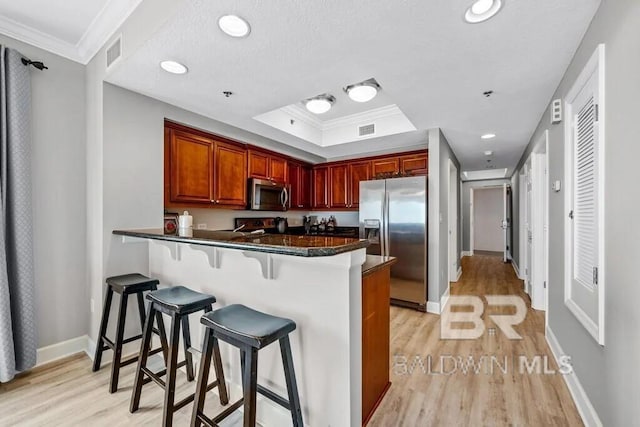 kitchen featuring stainless steel appliances, a tray ceiling, visible vents, and ornamental molding