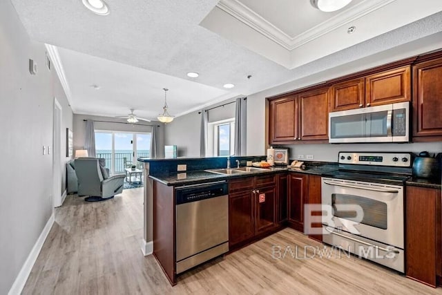 kitchen featuring dark countertops, light wood-style flooring, appliances with stainless steel finishes, ornamental molding, and a sink