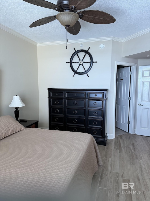 bedroom featuring a textured ceiling, ornamental molding, a ceiling fan, and light wood-style flooring