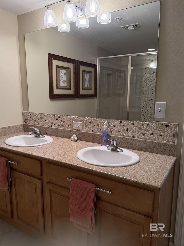 full bath featuring a sink, a shower stall, double vanity, and visible vents