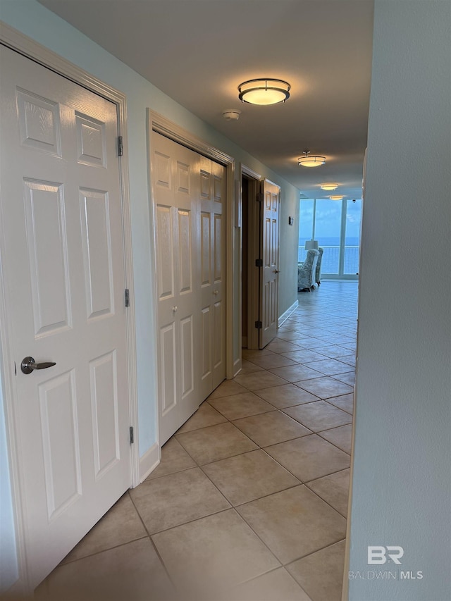 hall with baseboards and light tile patterned floors
