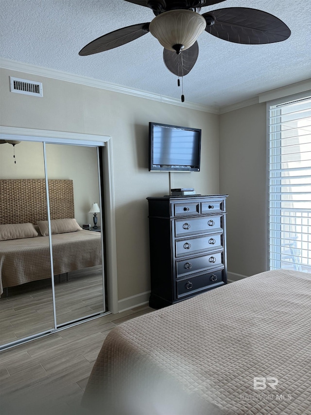 bedroom with visible vents, crown molding, multiple windows, and a closet