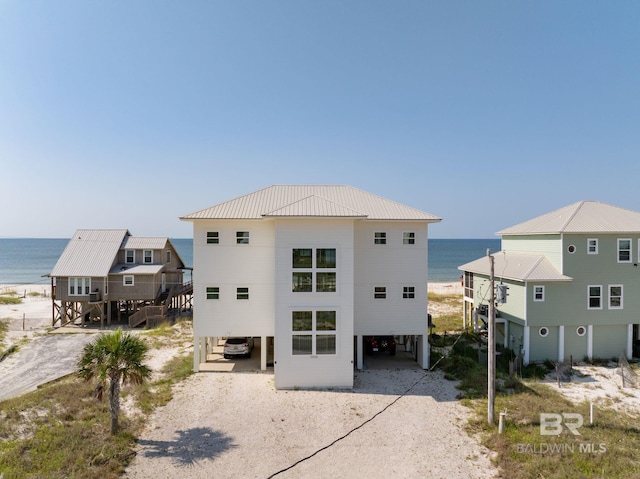 exterior space featuring a water view, driveway, metal roof, and a carport