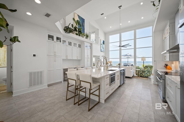 kitchen with visible vents, white cabinetry, light countertops, appliances with stainless steel finishes, and glass insert cabinets