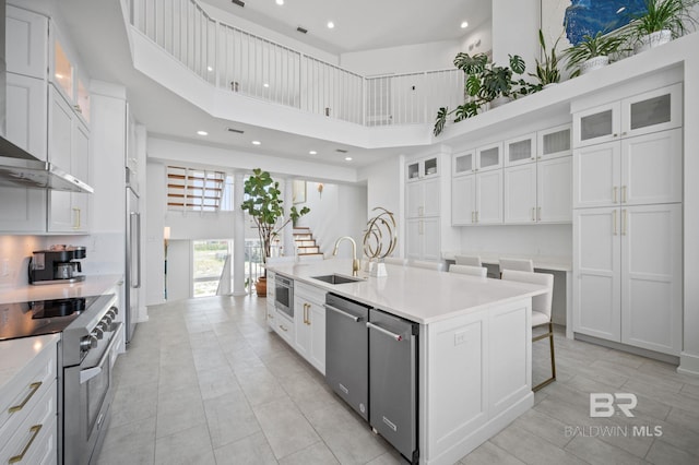 kitchen with white cabinetry, light countertops, an island with sink, and high quality appliances