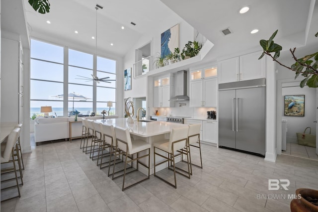 kitchen featuring glass insert cabinets, appliances with stainless steel finishes, light countertops, wall chimney range hood, and white cabinetry