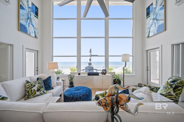 living area with a water view, a healthy amount of sunlight, and a high ceiling