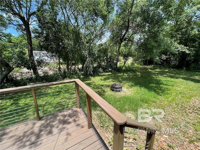 wooden terrace featuring a lawn and a fire pit