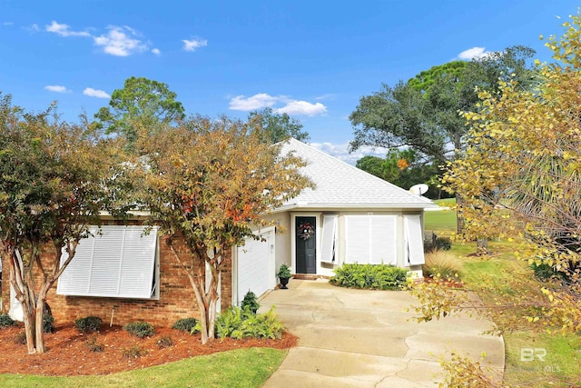 view of front of house featuring driveway, a shingled roof, brick siding, and a garage
