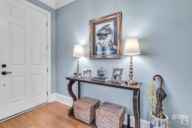 entrance foyer with wood finished floors, ornamental molding, and baseboards