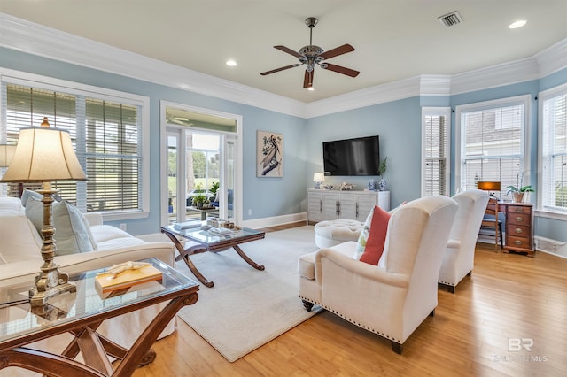 living area featuring a ceiling fan, visible vents, baseboards, and a healthy amount of sunlight