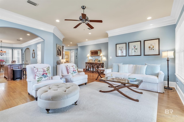 living room with arched walkways, visible vents, a ceiling fan, and light wood-style floors