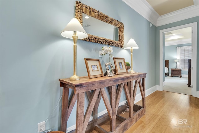 hallway with baseboards, visible vents, light wood-style floors, and crown molding