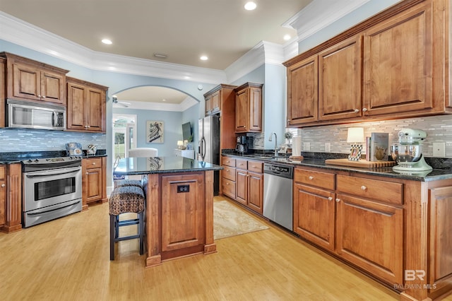 kitchen featuring a center island, light wood-style flooring, a sink, and appliances with stainless steel finishes