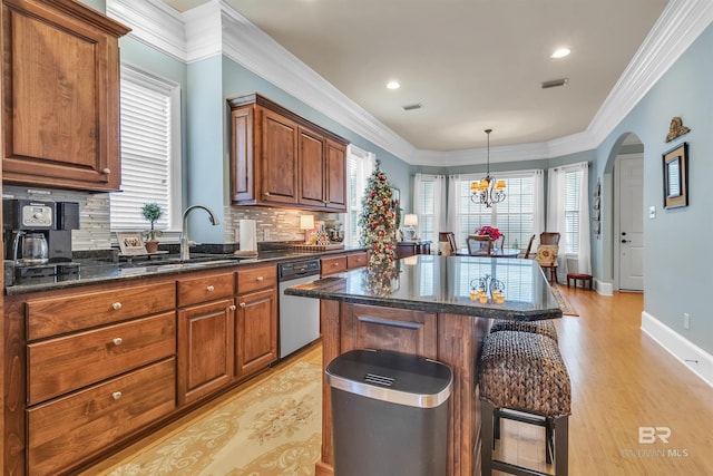 kitchen with a kitchen breakfast bar, decorative backsplash, stainless steel dishwasher, a sink, and visible vents