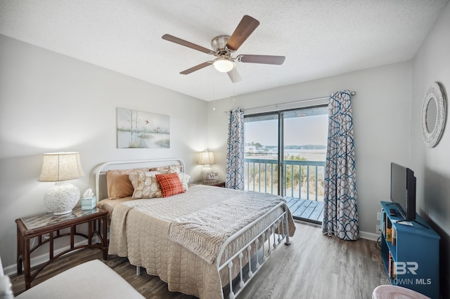 bedroom with access to outside, a textured ceiling, and dark hardwood / wood-style flooring