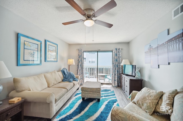 living room with ceiling fan, light hardwood / wood-style flooring, and a textured ceiling