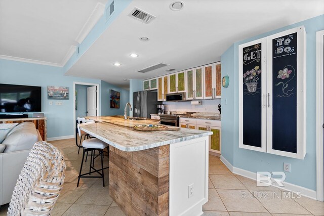 kitchen featuring light tile patterned floors, stainless steel appliances, a sink, a breakfast bar, and recessed lighting