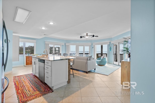 kitchen featuring a sink, open floor plan, stainless steel appliances, light tile patterned floors, and a center island with sink
