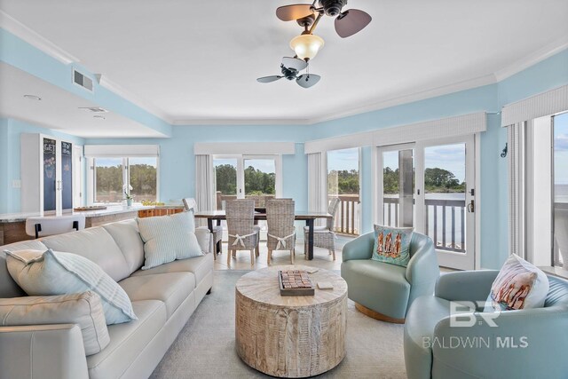 living area with crown molding, plenty of natural light, and a ceiling fan