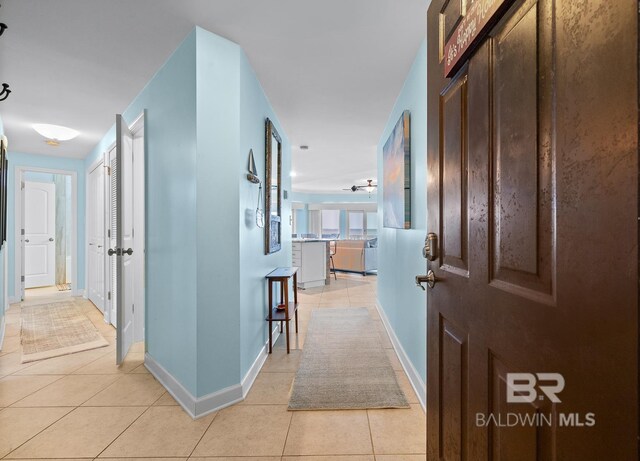 hall with light tile patterned flooring and baseboards