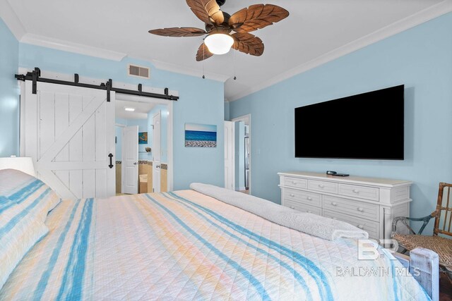 bedroom with ornamental molding, a barn door, a ceiling fan, and ensuite bathroom