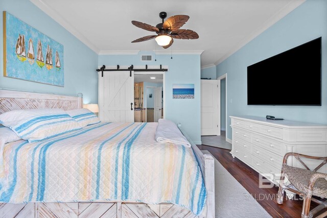 bedroom featuring ornamental molding, wood finished floors, a barn door, and a ceiling fan