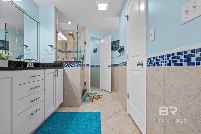 full bathroom featuring tile walls, tile patterned floors, a shower stall, vanity, and a wainscoted wall