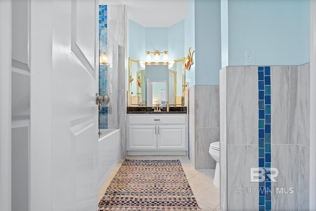 full bathroom with tile walls, toilet, tile patterned floors, vanity, and a bathtub