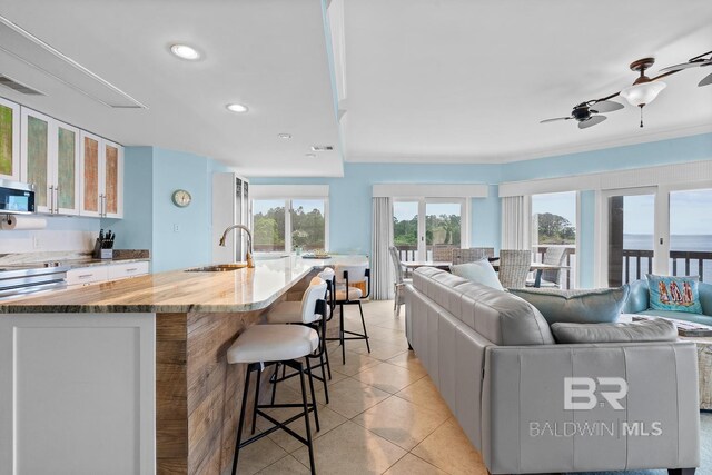 living room featuring light tile patterned flooring, a ceiling fan, recessed lighting, and crown molding