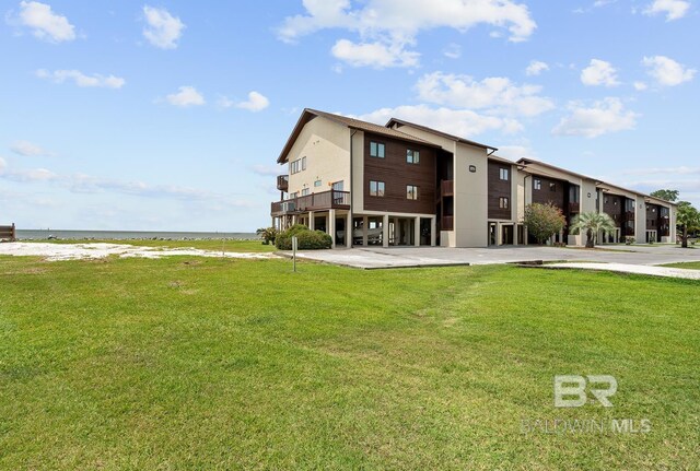rear view of house featuring view of water and beach and a lawn