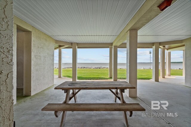 sunroom / solarium with a water view, plenty of natural light, and concrete floors