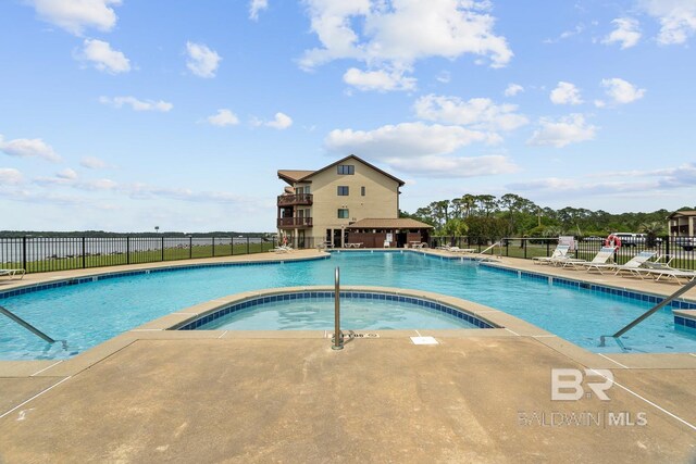 community pool featuring fence, a hot tub, and a patio