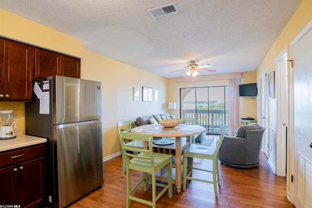 kitchen with ceiling fan, stainless steel refrigerator, a textured ceiling, and hardwood / wood-style flooring