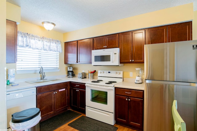 kitchen with white appliances, a textured ceiling, sink, and light wood-type flooring