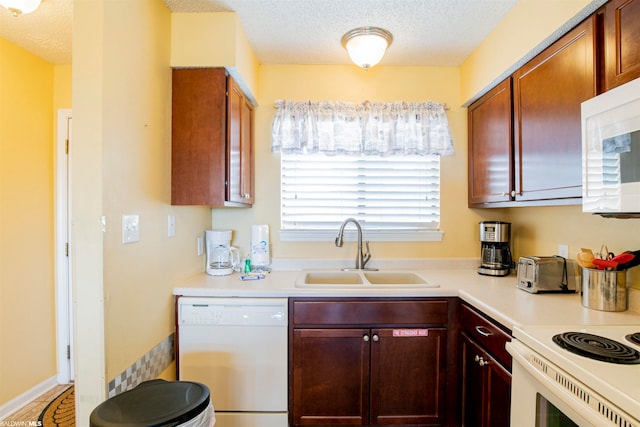 kitchen with white appliances, sink, and a textured ceiling