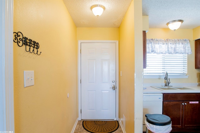 doorway to outside featuring light tile floors, a textured ceiling, and sink