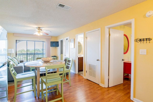 dining room with ceiling fan, light wood-type flooring, and a textured ceiling