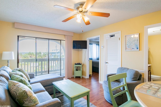 living room featuring ceiling fan, a wealth of natural light, dark hardwood / wood-style floors, and a textured ceiling