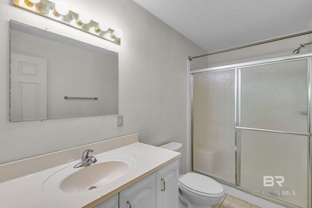 bathroom with a textured ceiling, vanity, toilet, and a shower with door