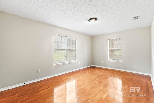 unfurnished room with a textured ceiling and hardwood / wood-style floors