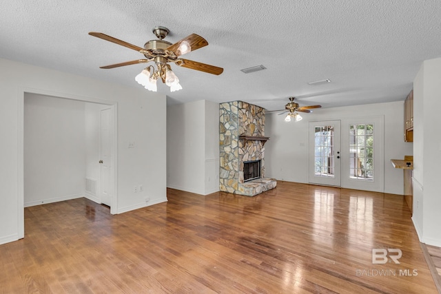 unfurnished living room featuring a textured ceiling, a fireplace, ceiling fan, and hardwood / wood-style flooring